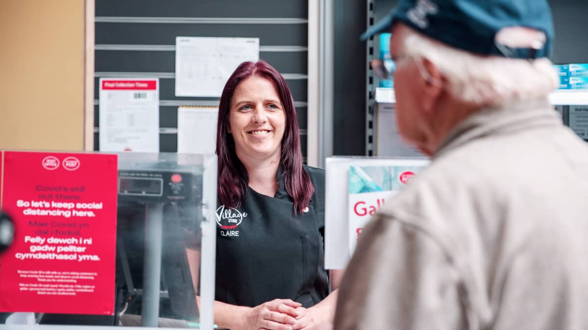 Woman at the post office counter serving a customer, smiling