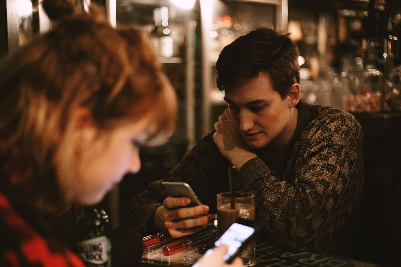 Woman and man looking down at their phones in a bar