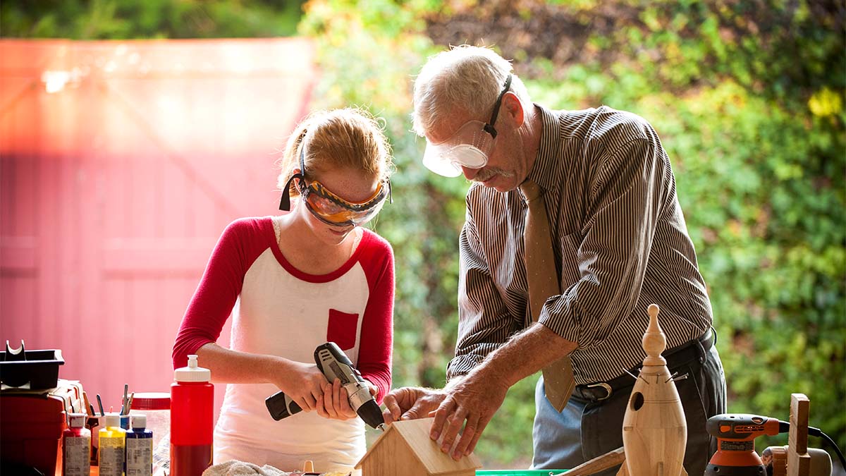 Father and daughter using DIY tools together building a wooden house