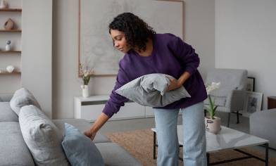 a person decluttering a sofa with too many pillows