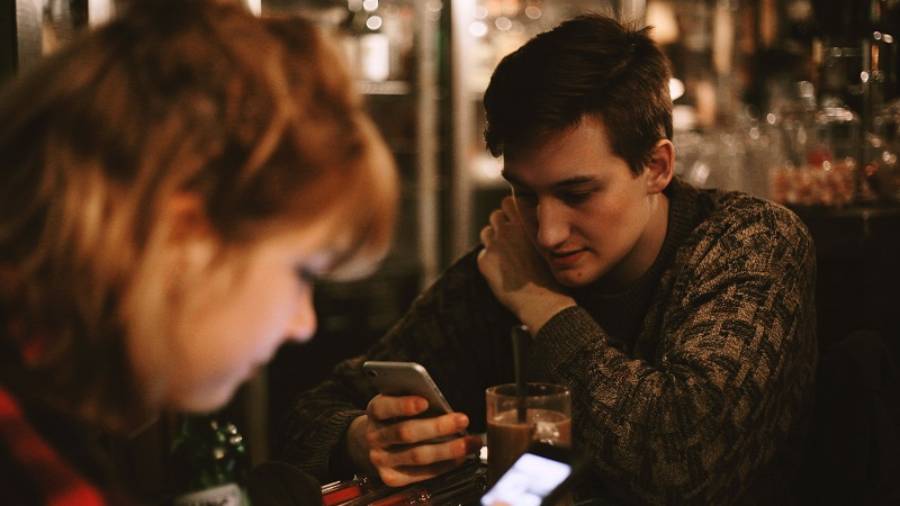 Woman and man looking down at their phones in a bar