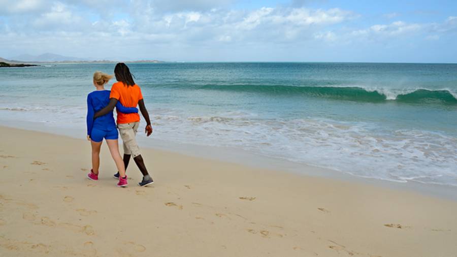 Couple strolling along a sandy beach looking out to sea in the Canary Islands