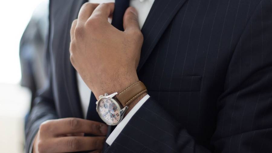 Close up of man wearing smart watch and suit adjusting his tie
