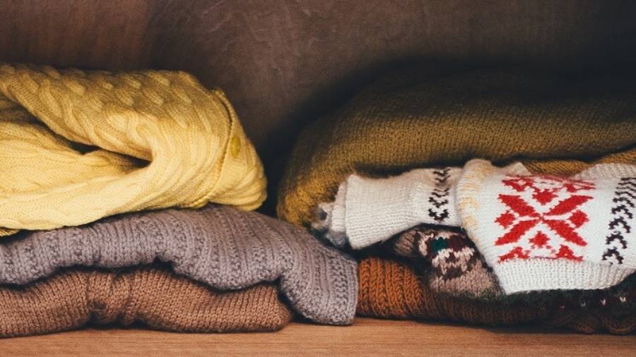 Various jumpers piled up on a clothes shelf