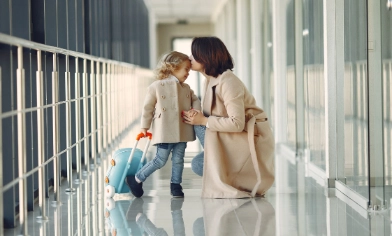 Mother giving her daughter a kiss in the airport before travelling