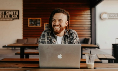 A person sitting at a table working on a laptop, in a room with modern decor.