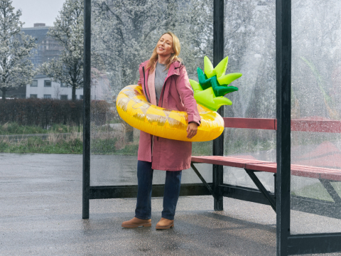a person wearing a large yellow pineapple pool float in a bus shelter
