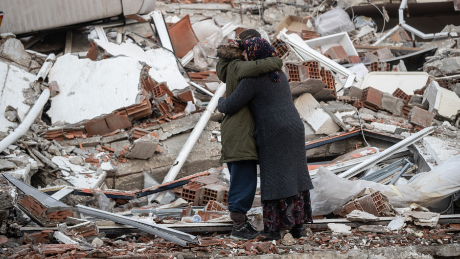 two people hugging in front of rubble