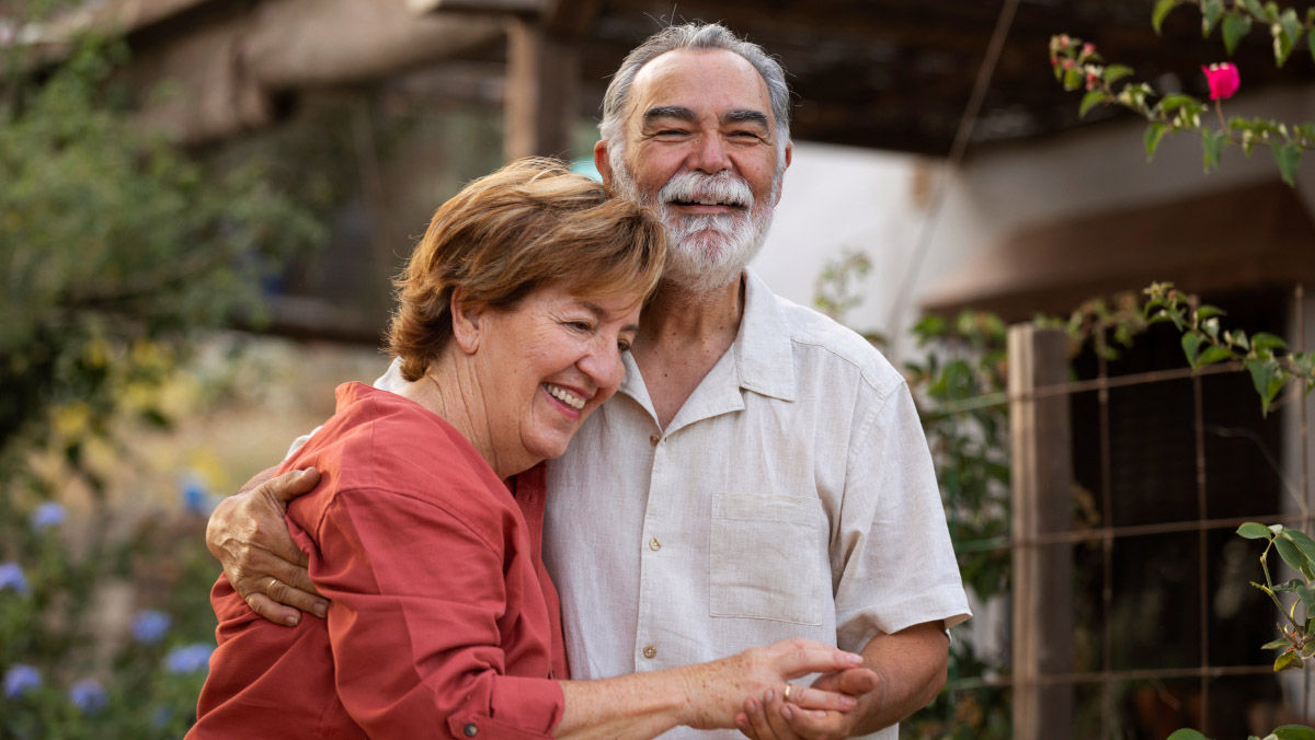 an elderly couple embracing in a garden