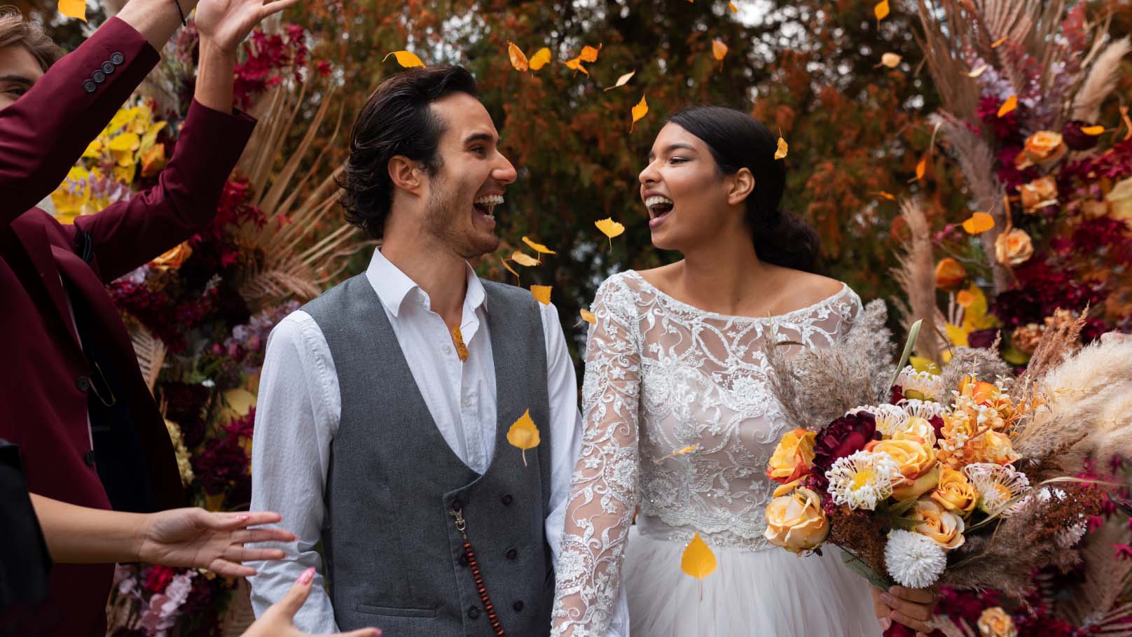 a newly married couple broadly smiling as their guests shower them with flower petals