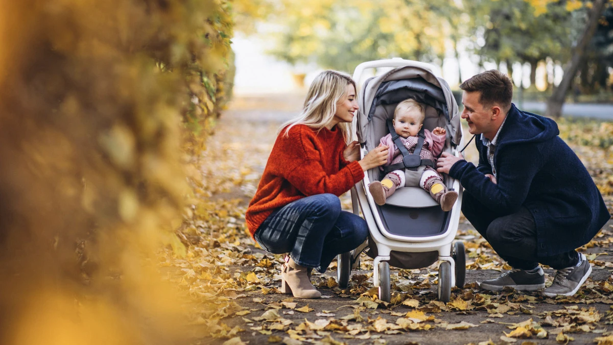 a couple interacting with a baby in a pram