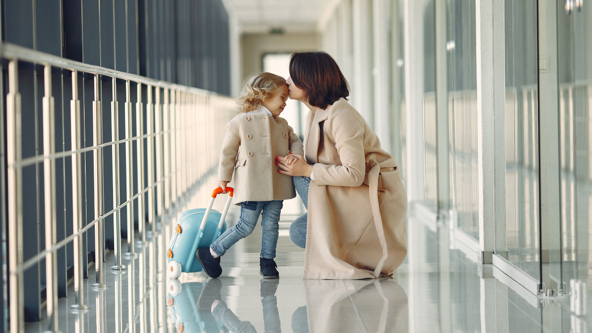 Mother giving her daughter a kiss in the airport before travelling